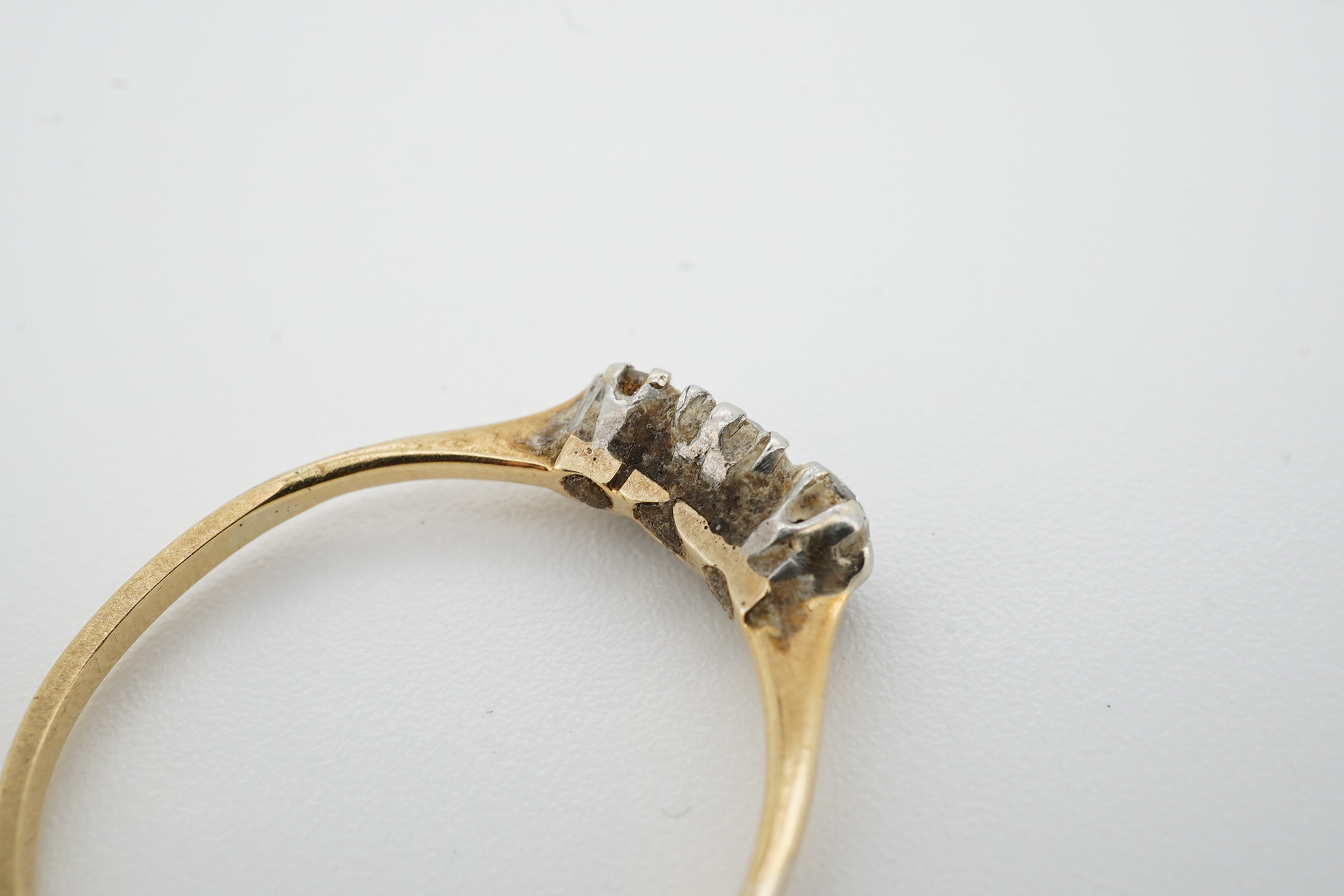 A yellow metal and three stone diamond set ring, size R/S, gross weight 2 grams. Condition - poor to fair